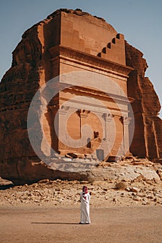 Vertical shot of a man standing in front of the Tomb of Lihyan son of Kuza in Saudi Arabia photo