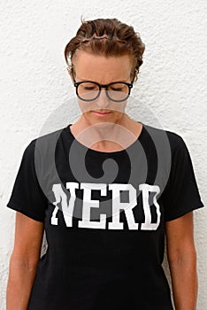 Vertical shot of mature nerd woman looking down while standing against white background outdoors