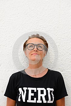 Vertical shot of mature nerd woman looking up to copy space while standing against white background outdoors
