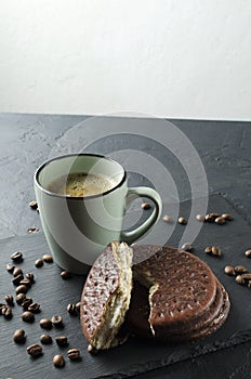 Vertical shot of mau og coffee and tasty sweet chocolate biscuits on the black surface