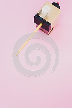 Vertical shot of a mechanical pencil sharpener on a pink surface