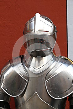 Vertical shot of a medieval knight armor against a red wall