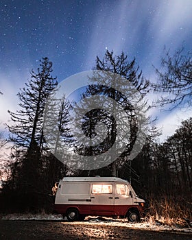 Vertical shot of a Mercedes Benz Astro van parked in a forest