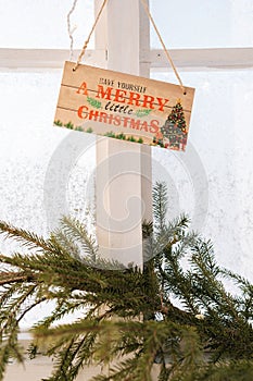 Vertical shot of Merry Christmas sign on wall with frozen window on sunny day. Closeup of sign on door at Christmas