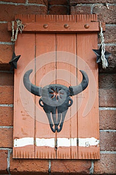 Vertical shot of metal bull head on wooden surface . Meat shop concept