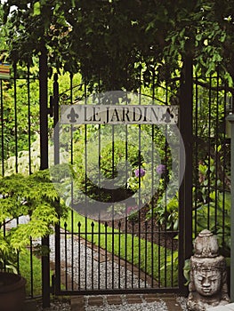Vertical shot of a metal gate with the French words 'Le Jardin' - Translation: The Garden photo