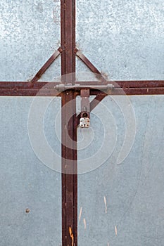 Vertical shot of a metal gate with a rusty crossbar lock