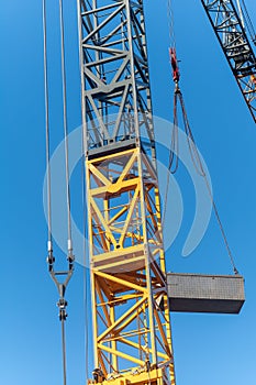 Vertical shot of a metal yellow gray industrial crane in a blue sky