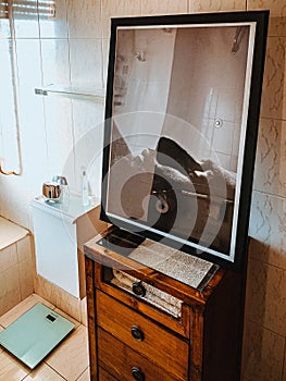 Vertical shot of a mirror with the reflection of the bathroom interior on the wooden shelf