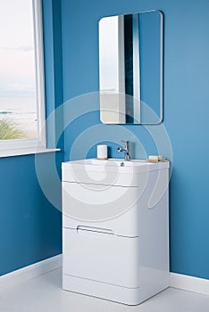 Vertical shot of a modern white sink with drawers in a blue bathroom