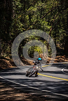 Vertical shot of a motorcyclist driving with one leg out on rural mountain road