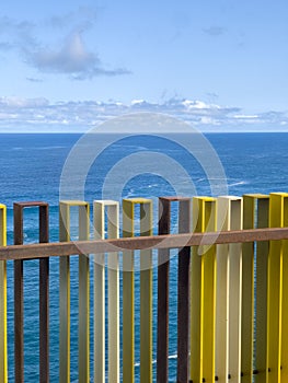 Vertical shot of a multicolored fence with the sea in the background in Martianez Beach, Tenerife.