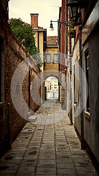 Vertical shot of a narrow street with an arched passage