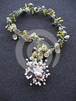 Vertical shot of a necklace made of shells and pearls on a gray surface