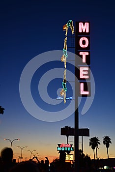 Vertical shot of a neon motel sign on the background of the sunset in the sky