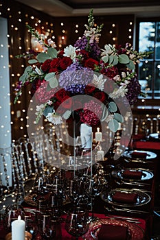 Vertical shot of a nice elegant red table setting for a party, decorated with candles and flowers