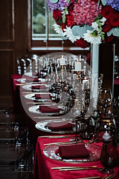 Vertical shot of a nice elegant red table setting for a party, decorated with candles and flowers