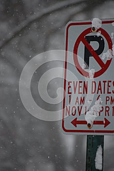 Vertical shot of a "no parking" sign with the specified time outdoors on a snowy winter day