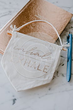 Vertical shot of a notebook, a pen, and a banner that says inhale and exhale