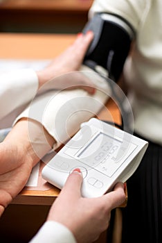 vertical shot of a nurse& x27;s hand checking a patient& x27;s blood pressure in a hospital room.