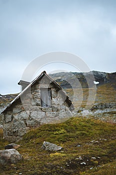 Vertical shot of an old abandoned cabin in a grassy field in Finse, Norway