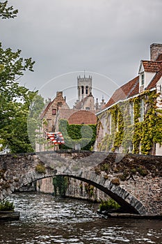 Vertical shot of an old arch bridge with the Belfry of Bruges in the background in Bruges, Belgium