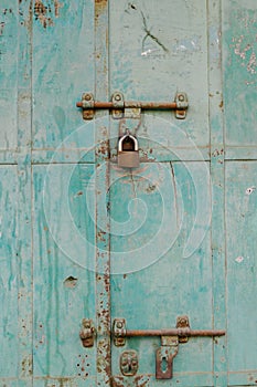Vertical shot of an old blue peeling paint door,rusty hinges,padlock,Mandawa haveli Rajasthan India