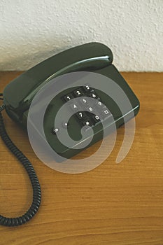 Vertical shot of an old dark green telephone on a wooden surface