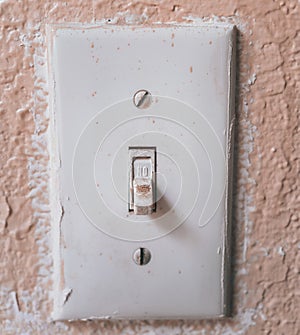 Vertical shot of an old light switch on the painted wall