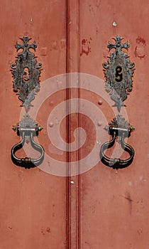 Vertical shot of an old metal door knocker on a red door