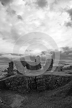 Vertical shot of old ruins on a cliff under a gloomy sky in grayscale