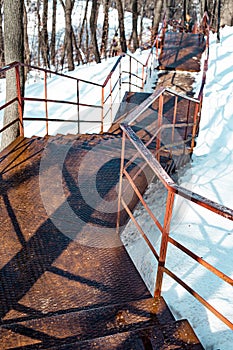 Vertical shot of an old rusty stairway in a snow-covered park