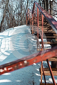 Vertical shot of an old rusty stairway in a snow-covered park