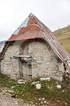 Vertical shot of an old stone building with a rusty metal roof in a rural area