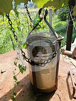 Vertical shot of an old tin well bucket with attached chains