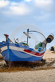 Vertical shot of an old weathered fishing boat on a beach sand