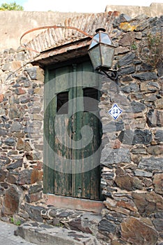 Vertical shot of old weathered green wooden door of a small stone building with number 54