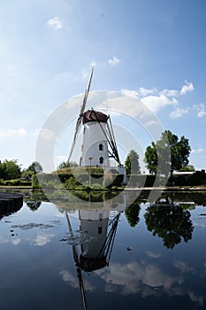 Vertical shot of an old windmill in the countryside by the lake or pond