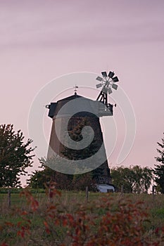 Vertical shot of an old windmill in a field in the countryside at sunset