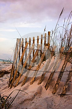 Vertical shot of an old wooden fence on the sandy beach during sunset
