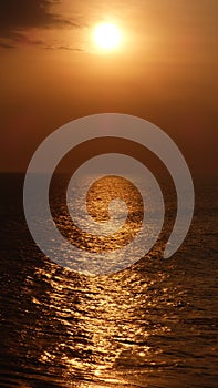 Vertical shot of the orange evening sky with the reflection above the ocean in Bali, indonesia