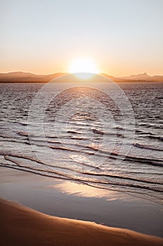 Vertical shot of an orange sunset sky over Little Wategos Beach in Byron Bay, Australia