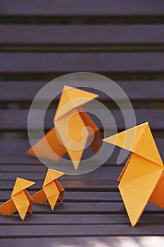 Vertical shot of an origami figures  family on a park bench