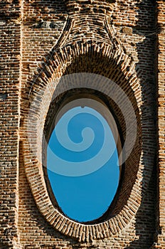 Vertical shot of an oval window in a brick wall of a historical building