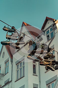 Vertical shot of pairs of sneakers hanging on a wire outdoors