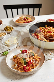 Vertical shot of pasta with vegetables and ingredients on a white table