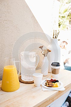 Vertical shot of pastries, pitchers of juice, and water beside white vases on a wooden surface