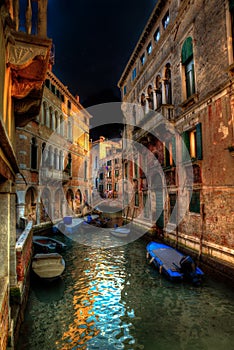 Vertical shot of a peaceful canal between old buildings in nighttime Venice, Italy