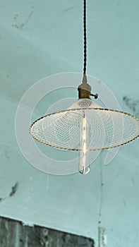 Vertical shot of a pendant light hanging from blue ceil with long lamp