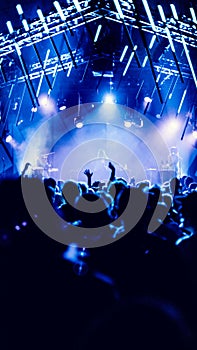 Vertical shot of people from back during the Roskilde Festival, Denmark in a hall with blue lights